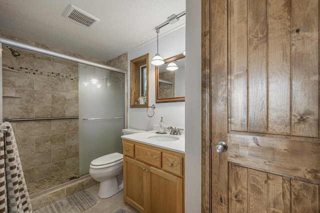 bathroom with a textured ceiling, vanity, toilet, and an enclosed shower