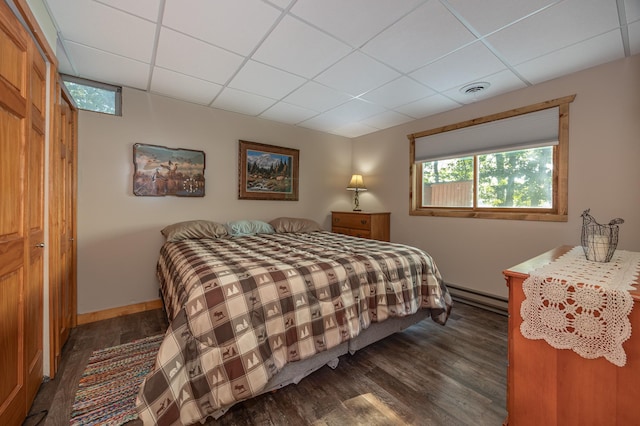 bedroom with a baseboard heating unit, a closet, and dark hardwood / wood-style flooring