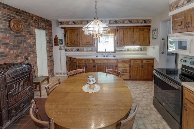 kitchen with stainless steel electric range oven, brick wall, pendant lighting, sink, and a chandelier