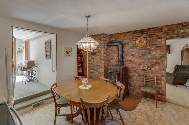 dining space with a textured ceiling, brick wall, and a wood stove