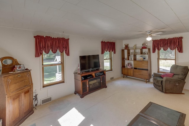 living room featuring ceiling fan, carpet, and a wealth of natural light