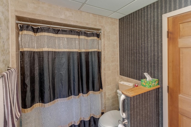 bathroom with a drop ceiling, toilet, tile walls, and a shower with shower curtain