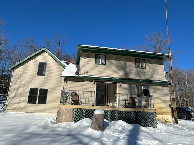 snow covered rear of property with a wooden deck