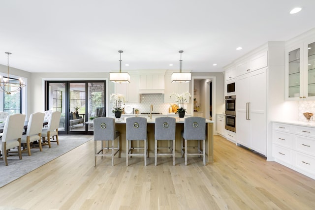 kitchen featuring pendant lighting, a kitchen bar, light hardwood / wood-style floors, and an island with sink