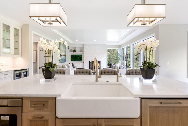 kitchen with a notable chandelier, ornamental molding, tasteful backsplash, beverage cooler, and sink