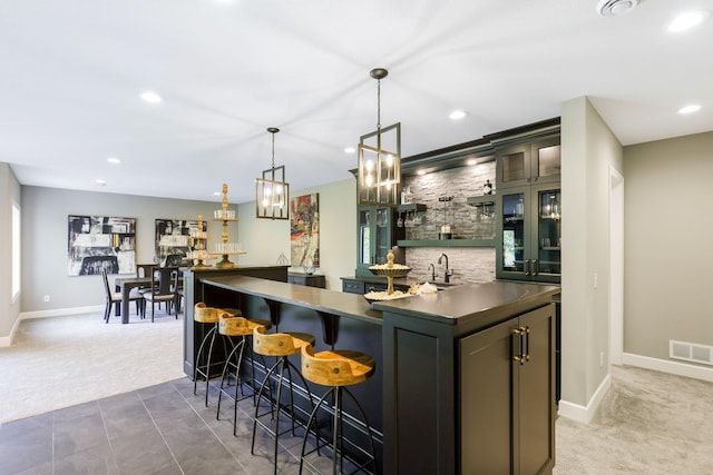 bar with hanging light fixtures, carpet flooring, sink, and a chandelier