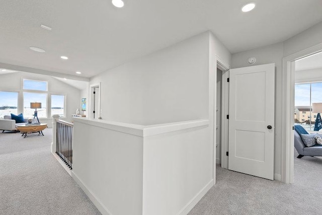 hallway with a wealth of natural light and light colored carpet