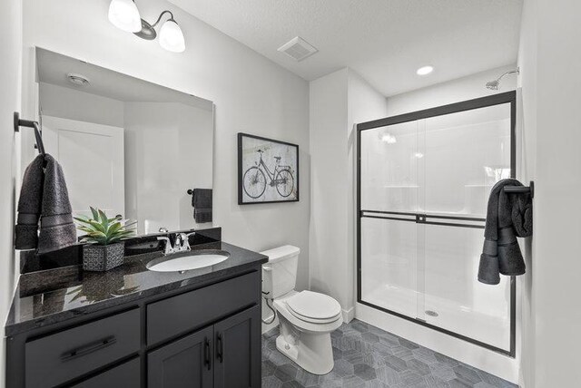 bathroom with vanity, toilet, walk in shower, and a textured ceiling