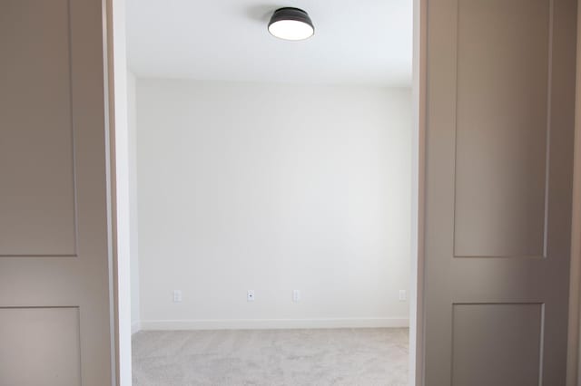 unfurnished room with light carpet and baseboards