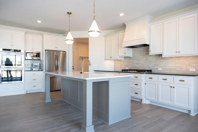 kitchen featuring stainless steel appliances, a sink, white cabinetry, dark countertops, and pendant lighting