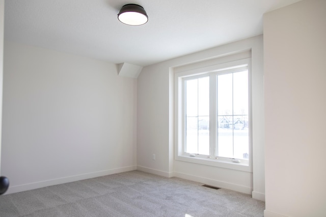 unfurnished room with baseboards, visible vents, and light colored carpet