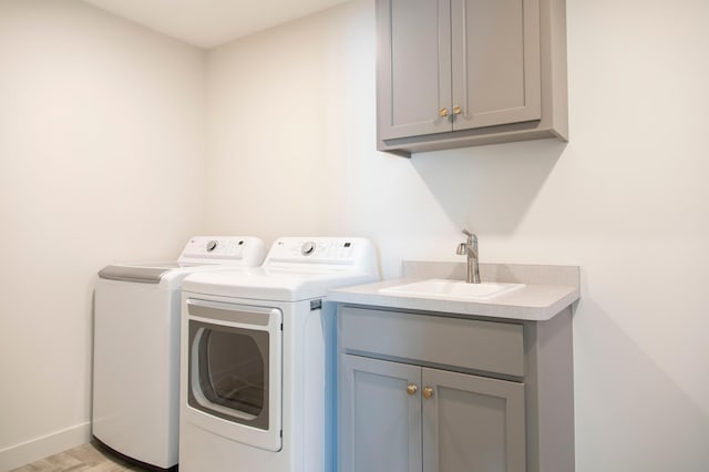 clothes washing area featuring washer and clothes dryer, a sink, cabinet space, and baseboards