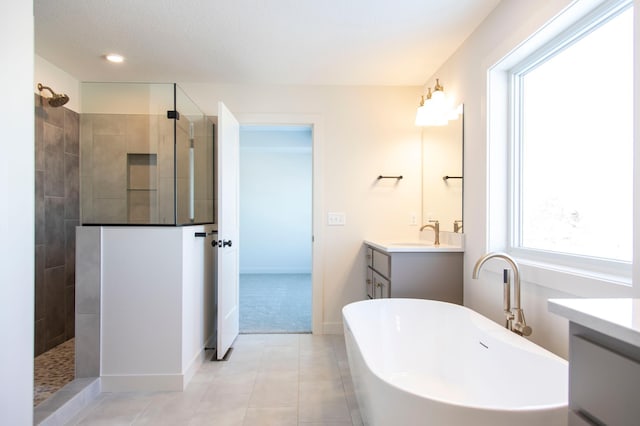 full bathroom featuring a soaking tub, vanity, a walk in shower, baseboards, and tile patterned floors