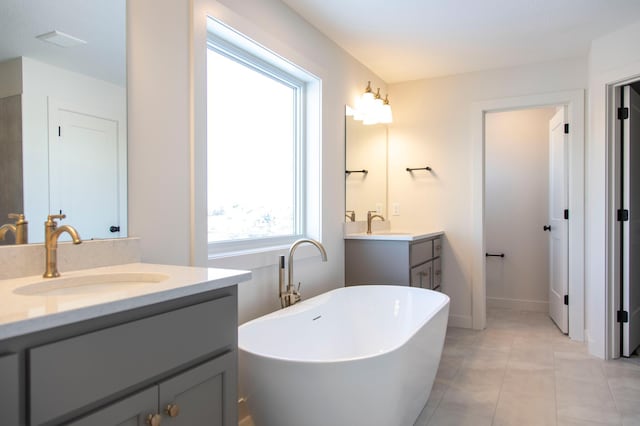 full bathroom featuring a freestanding bath, two vanities, a sink, and tile patterned floors