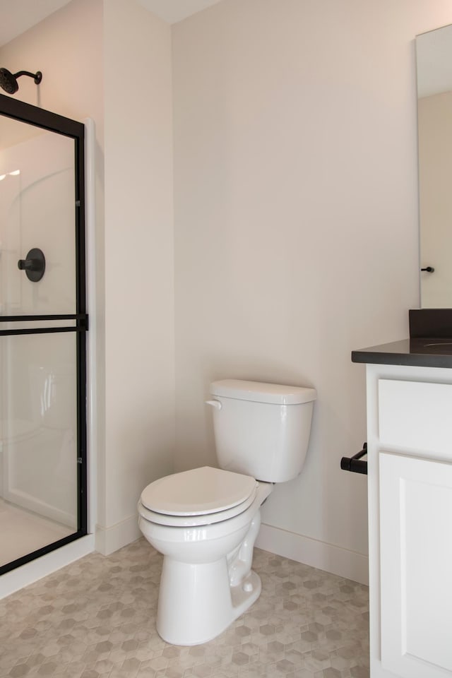 bathroom featuring toilet, baseboards, walk in shower, and vanity