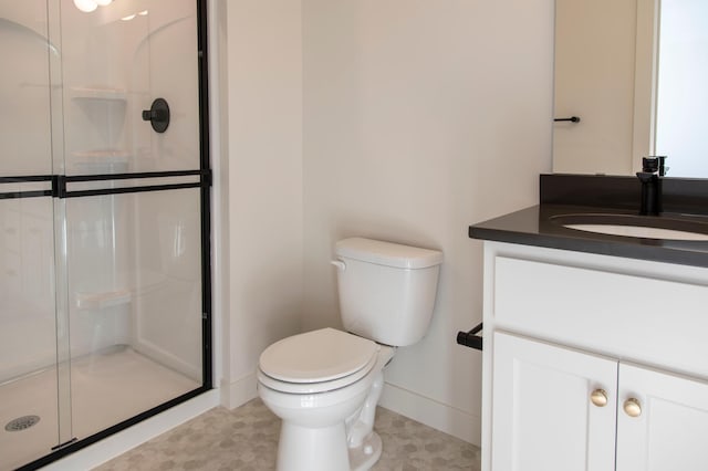 bathroom with a stall shower, baseboards, vanity, and toilet