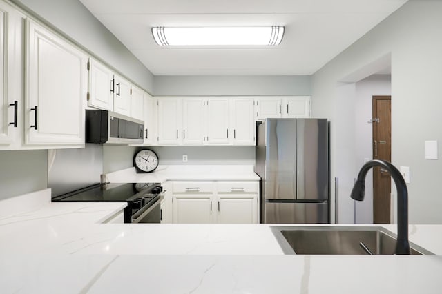 kitchen featuring white cabinetry, sink, stainless steel appliances, and light stone counters