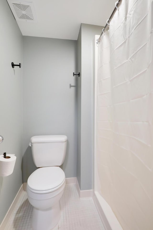 bathroom featuring tile patterned flooring, toilet, and a shower with curtain