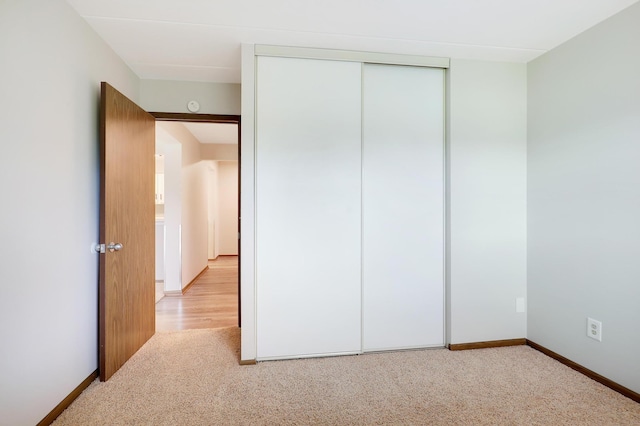 unfurnished bedroom featuring light colored carpet and a closet