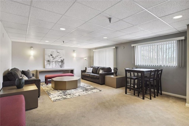 carpeted living room featuring a drop ceiling