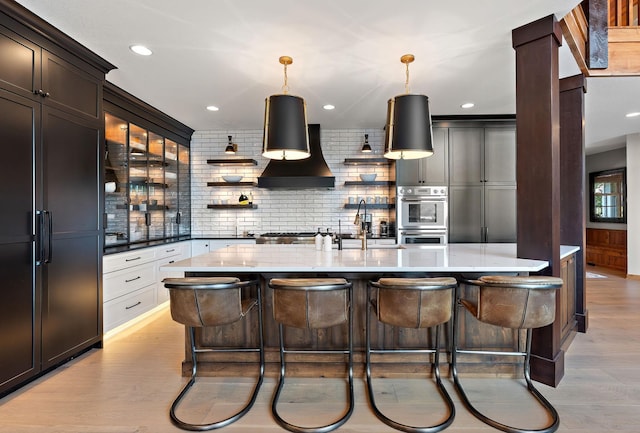 kitchen with pendant lighting, double oven, a breakfast bar area, and white cabinets