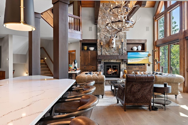 living room featuring a towering ceiling, a chandelier, a fireplace, and light wood-type flooring