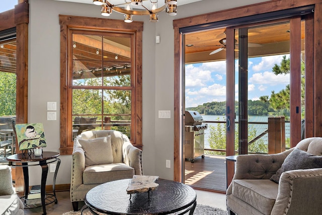 sitting room featuring ceiling fan with notable chandelier, a water view, and hardwood / wood-style floors