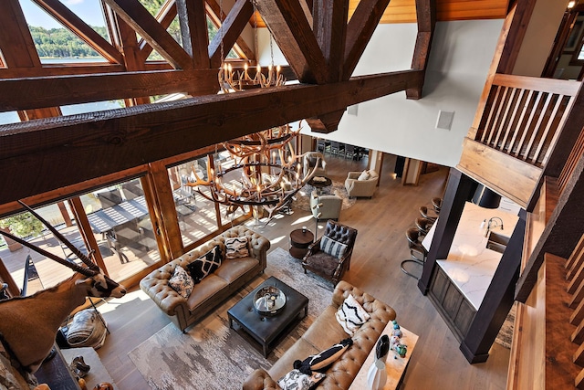 living room with an inviting chandelier, beamed ceiling, high vaulted ceiling, and hardwood / wood-style flooring