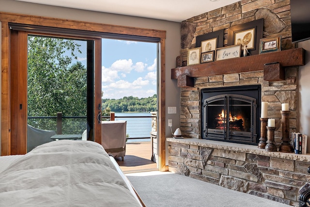 bedroom featuring a water view, access to exterior, and a fireplace