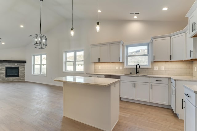 kitchen with white cabinets, light wood-type flooring, decorative light fixtures, and sink