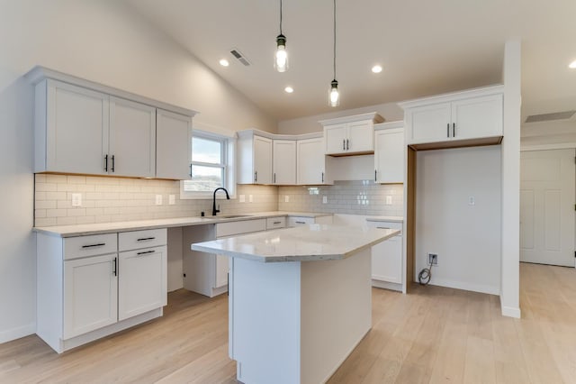 kitchen with a center island, white cabinets, pendant lighting, and light wood-type flooring