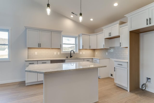 kitchen featuring light hardwood / wood-style floors, decorative light fixtures, a center island, and plenty of natural light