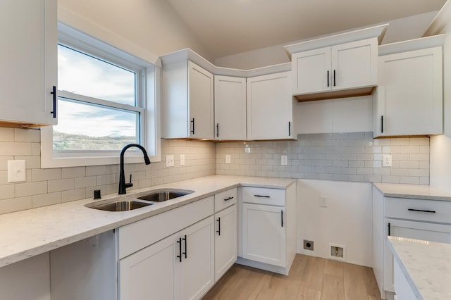 kitchen featuring white cabinets, decorative backsplash, light hardwood / wood-style flooring, and sink