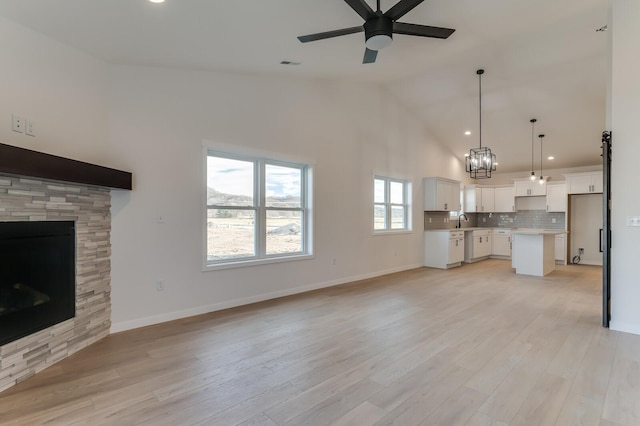 unfurnished living room featuring a fireplace, ceiling fan, light hardwood / wood-style flooring, and sink