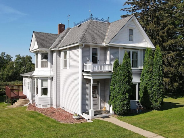 view of front facade with a balcony and a front yard