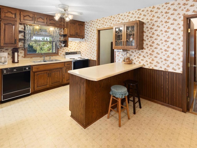 kitchen featuring electric range oven, dishwasher, sink, a kitchen breakfast bar, and kitchen peninsula