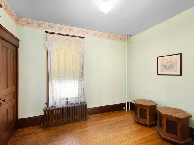 spare room featuring radiator heating unit and light hardwood / wood-style flooring