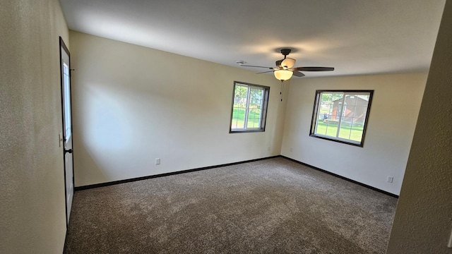 spare room with ceiling fan and dark carpet