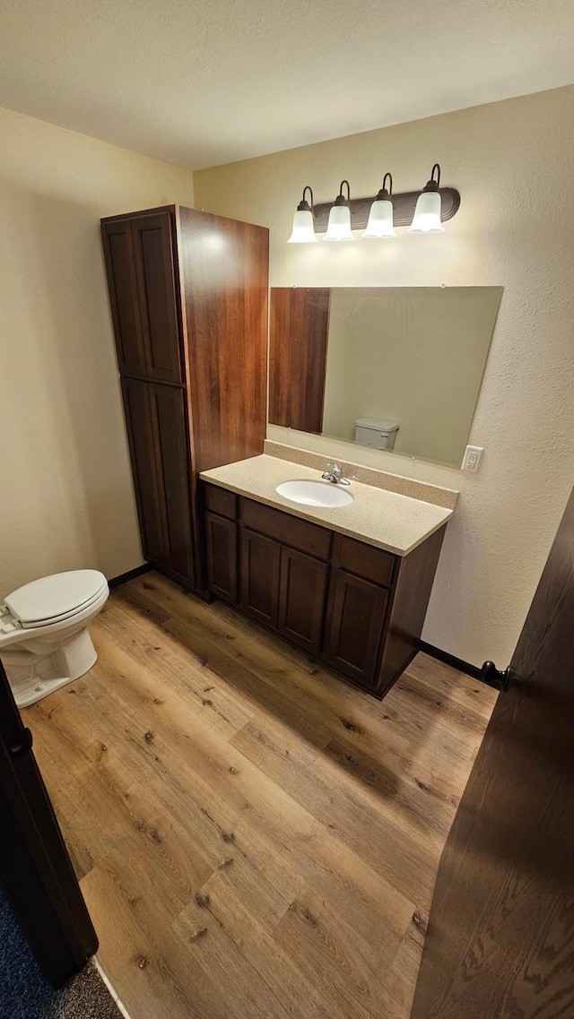 bathroom featuring vanity, wood-type flooring, and toilet