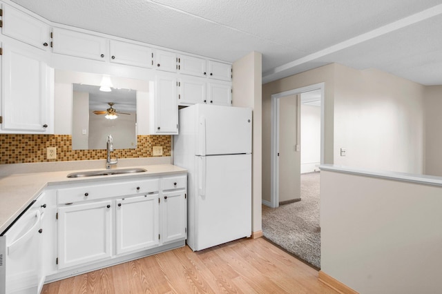 kitchen with white appliances, light hardwood / wood-style floors, white cabinetry, sink, and ceiling fan