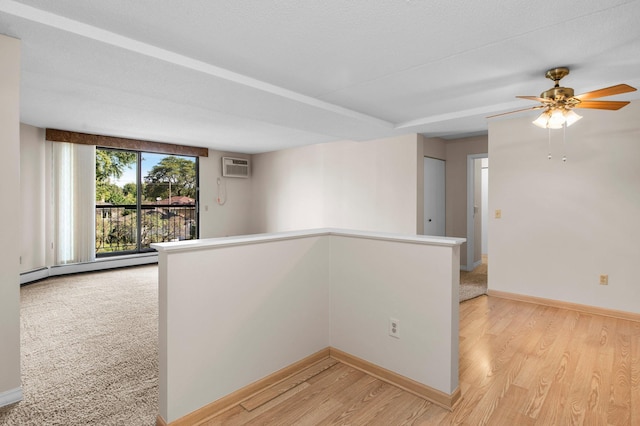 empty room featuring a textured ceiling, baseboard heating, ceiling fan, and light hardwood / wood-style floors