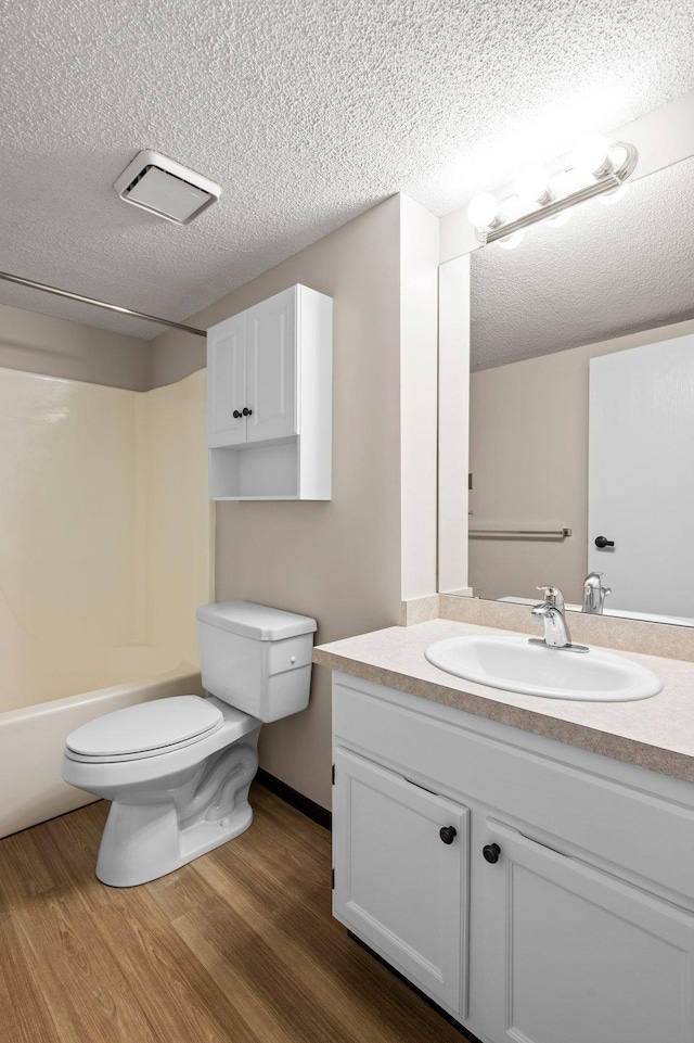 full bathroom with toilet, vanity, a textured ceiling, shower / bathing tub combination, and wood-type flooring