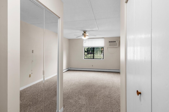 spare room featuring a baseboard heating unit, a wall mounted AC, ceiling fan, and carpet