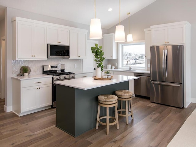 kitchen featuring lofted ceiling, wood-type flooring, appliances with stainless steel finishes, and white cabinets