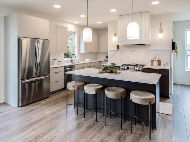 kitchen featuring pendant lighting, stainless steel appliances, light hardwood / wood-style flooring, and a kitchen island