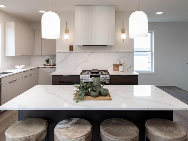 kitchen with light stone counters, a kitchen island, decorative light fixtures, and high end range