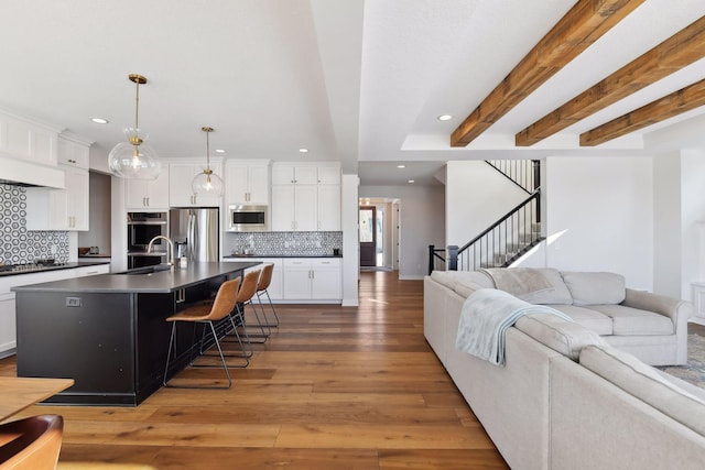 living room with beamed ceiling, hardwood / wood-style floors, and sink