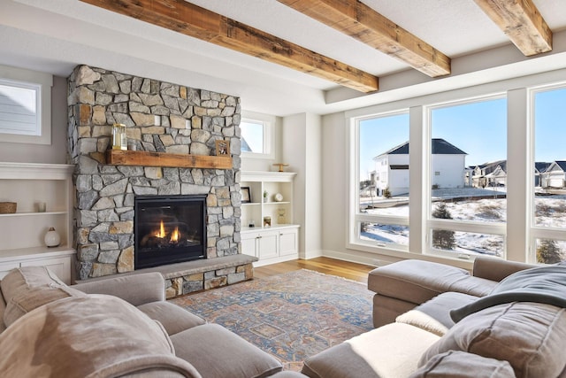 living room featuring a fireplace, a textured ceiling, light hardwood / wood-style flooring, and beamed ceiling