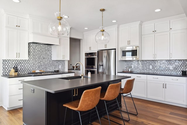 kitchen with light wood-type flooring, stainless steel appliances, sink, and a center island with sink