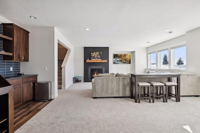 carpeted living room featuring a large fireplace and a textured ceiling